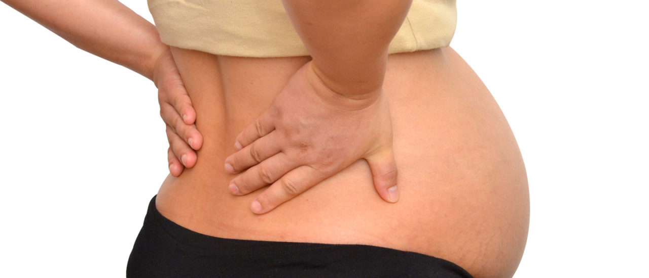 Pregnant woman bends over holding her back in pain